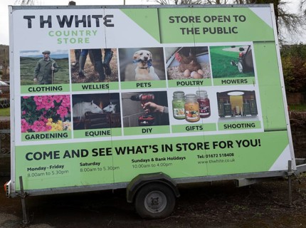 Mobile wheeled advertising hoarding for TH White country store shop, Marlborough, Wiltshire,
