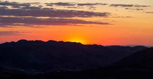 Sunset with glowing sky orange sun dropping behind hills. Photo taken looking south west from
