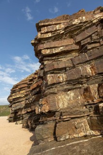 Tilted layers showing bedding planes in strata of sedimentary rock in coastal cliff at Odeceixe,