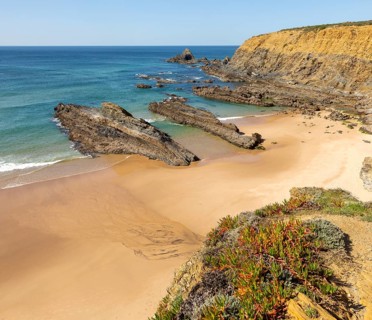Sandy beach Praia dos Alteirinhos, Zambujeira do Mar in bay between rocky headlands part of Parque