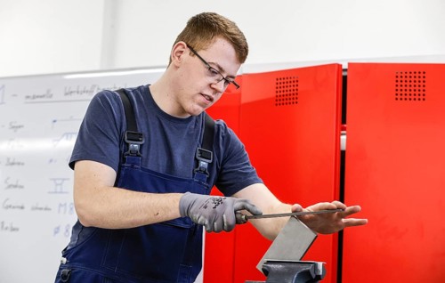 A trainee mechatronics technician works on a workpiece at a Deutsche Bahn training centre, Berlin,