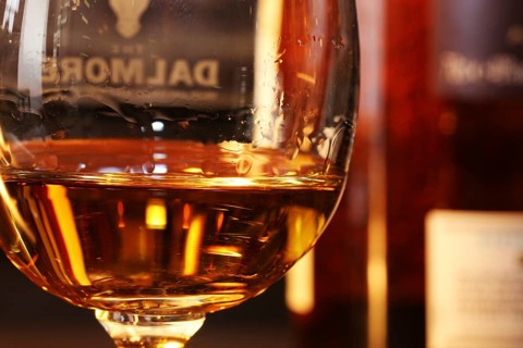 Close-up of a glass of whiskey with a bottle of Dalmore single malt in the background