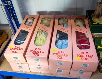 Pink boxes contains porcelain dolls on sale at auction