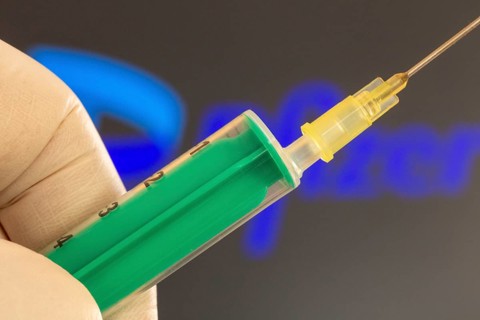 Corona vaccination/Pfizer symbol: close-up of an injection needle, with the Pfizer logo in the