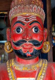 A close-up of a traditional red-faced statue of a man with a mustache, Matancherry, Jew Town,