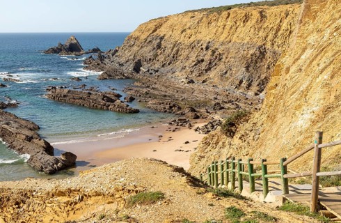 Rocky coastal landscape Praia dos Alteirinhos beach in bay with rocky headland part of Parque