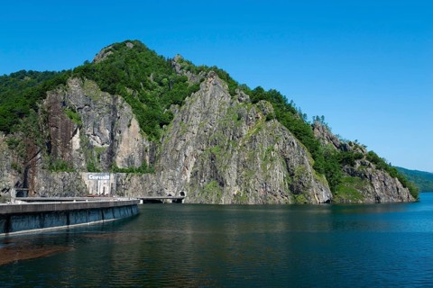 Reservoir surrounded by high green mountains under a clear blue sky, Vidraru Reservoir,