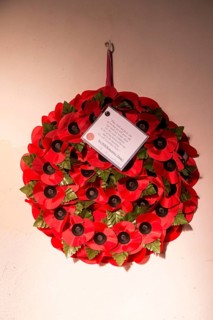 'We will remember them' remembrance day poppy wreath hanging from wall inside the church at South