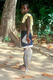 Young carrying fish on the island of La Digue, Seychelles, Africa