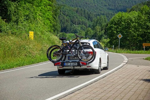 White car with Thule rear bike rack on a country road in Dahner Felsenland Germany