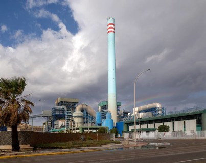 Rainbow in stormy sky behind tall blue industrial cement factory chimney, Carboneras, Almeria,