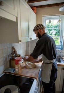 Young man kneading dough on kitchen surface