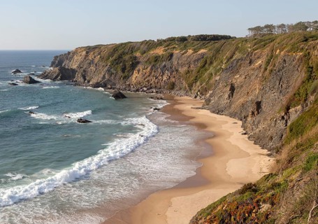 Secluded sandy beach in bay between rocky headlands at Parque Natural do Sudoeste Alentejano e