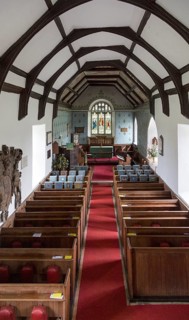 Raised angle view looking east down the nave towards the altar and east window with wooden pews,