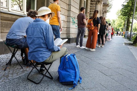 Vaccinated people in a queue sitting on folding chairs. Neighbourhood residents in the Tempelhof
