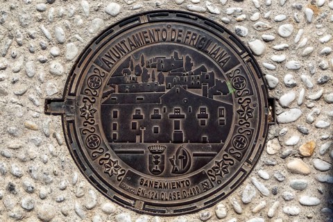Looking down at metal manhole cover design image of village, Frigiliana, Axarquia, Andalusia,