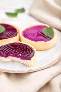 Sweet tartlets with jelly and milk cream with cup of coffee on a white wooden background and linen