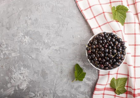 Fresh black currant in white bowl and linen textile on gray concrete background. top view, copy