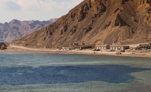 The coastline of the Red Sea with small resorts and the mountains in the background. Coral reef