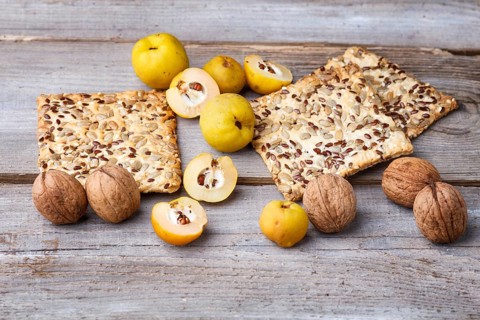Biscuits with flax, sesame and sunflower seeds and yellow quince fruit on a rustic wooden