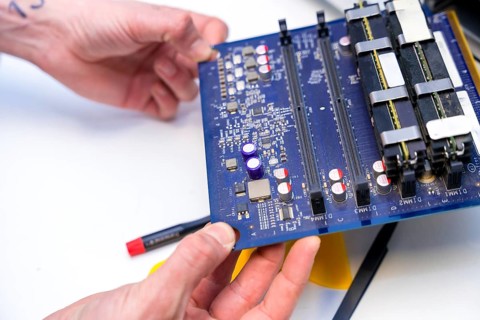 Close-up of the hands of a technician holding an electronic component of computer in a workshop