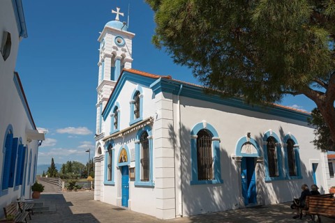 Church on a sunny day, people sitting on park benches in the shade, Monastery of St Nicholas,