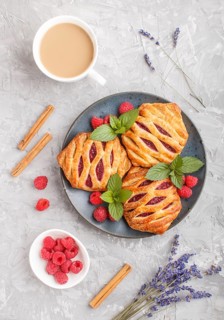 Puff pastry buns with strawberry jam on blue ceramic plate on gray concrete background, cup of