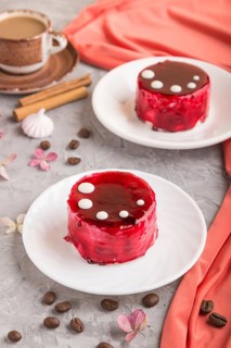 Red cake with souffle cream with cup of coffee on a gray concrete background and red textile. side