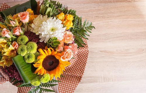 Bouquet of alstroemeria, sunflower, roses, chrysanthemum on a wooden background. floristic