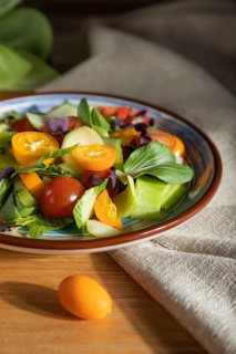 Vegetarian salad of pac choi cabbage, kiwi, tomatoes, kumquat, microgreen sprouts on a wooden