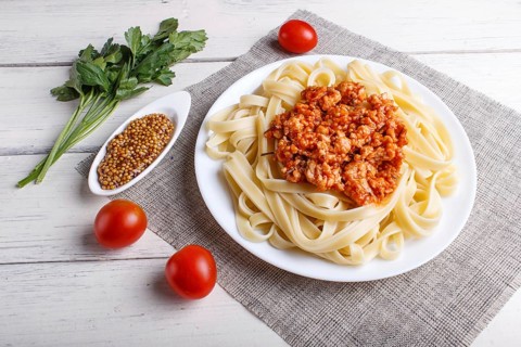 Fettuccine bolognese pasta with minced meat on white wooden background. top view, close up