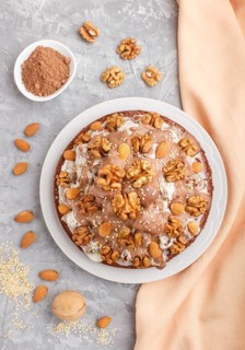 Homemade cake with milk cream, cocoa, almond, hazelnut on a gray concrete background with orange