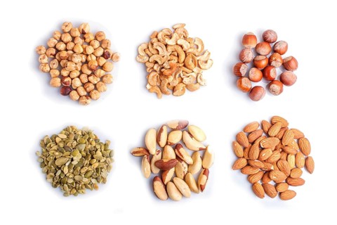 Piles of various nuts and seeds isolated on white background. hazelnut, brazil nut, almond, pumpkin