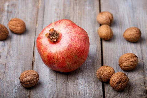 Ripe garnet with walnuts on a rustic wooden background