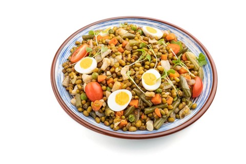 Mung bean porridge with quail eggs, tomatoes and microgreen sprouts isolated on a white background.