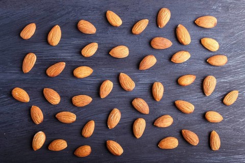 Pattern and texture made from almonds on black wooden background, flat lay. top view