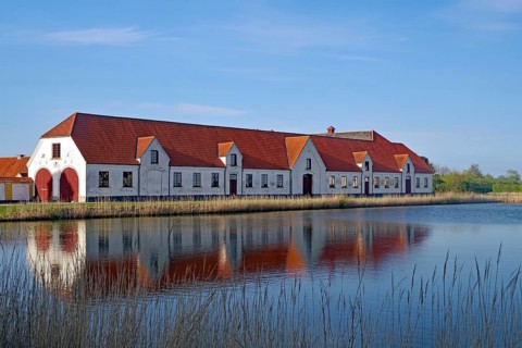 Large houses and the teahouse at Valdemars Slot are reflected in the calm water, Valdemars Slot,