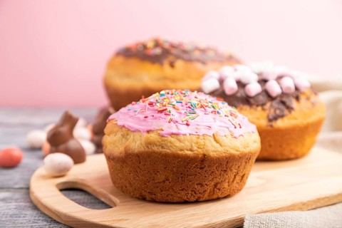 Homemade glazed and decorated easter pies with chocolate eggs and rabbits on a gray and pink