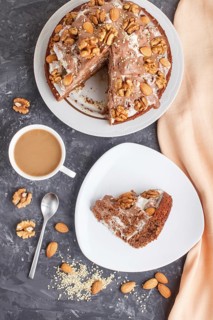Homemade cake with milk cream, cocoa, almond, hazelnut on a black concrete background with orange