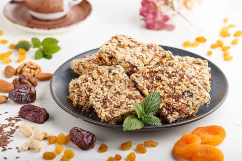 Homemade granola from oat flakes, dates, dried apricots, raisins, nuts in blue ceramic plate with a