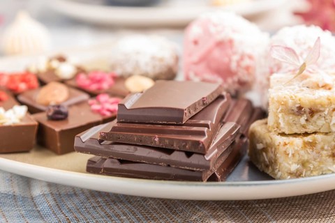 A pieces of homemade chocolate with coconut candies on a blue and brown textile. side view, close