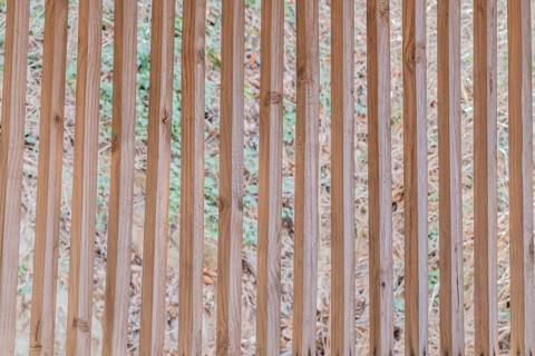 Vertical wooden slats in wall of building with blurred grassy hill in background in South Korea