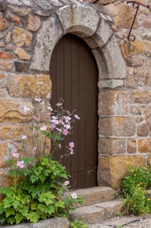House facade with entrance door, quarry stone house, small flower bed with autumn anemone, Ile de