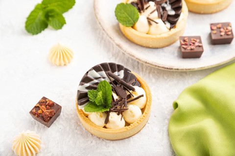 Sweet tartlets with chocolate and cheese cream with cup of coffee on a gray concrete background and