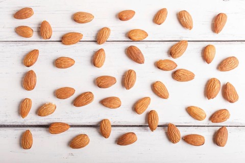 Pattern and texture made from almonds on white wooden background, flat lay. top view