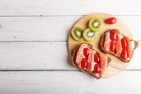 Smoked salmon sandwiches with butter and cherry tomatoes on white wooden background. top view, copy