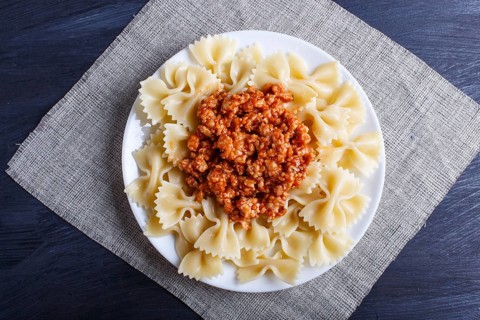 Farfalle bolognese pasta with minced meat on black wooden background. top view, close up