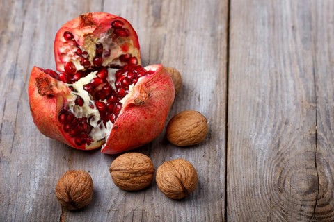 Ripe garnet with walnuts on a rustic wooden background