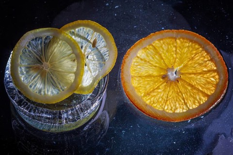 Transparent slices of fresh oranges and lemons on the glass with ice