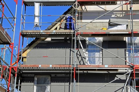 Construction workers insulate a house facade